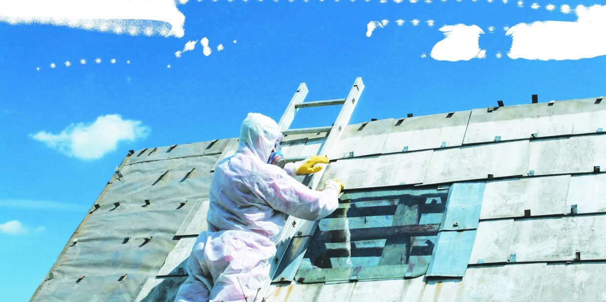 Licensed operative in full protective suit removing asbestos roof sheeting