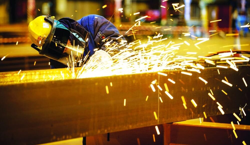 Welder grinding a steel beam with sparks flying