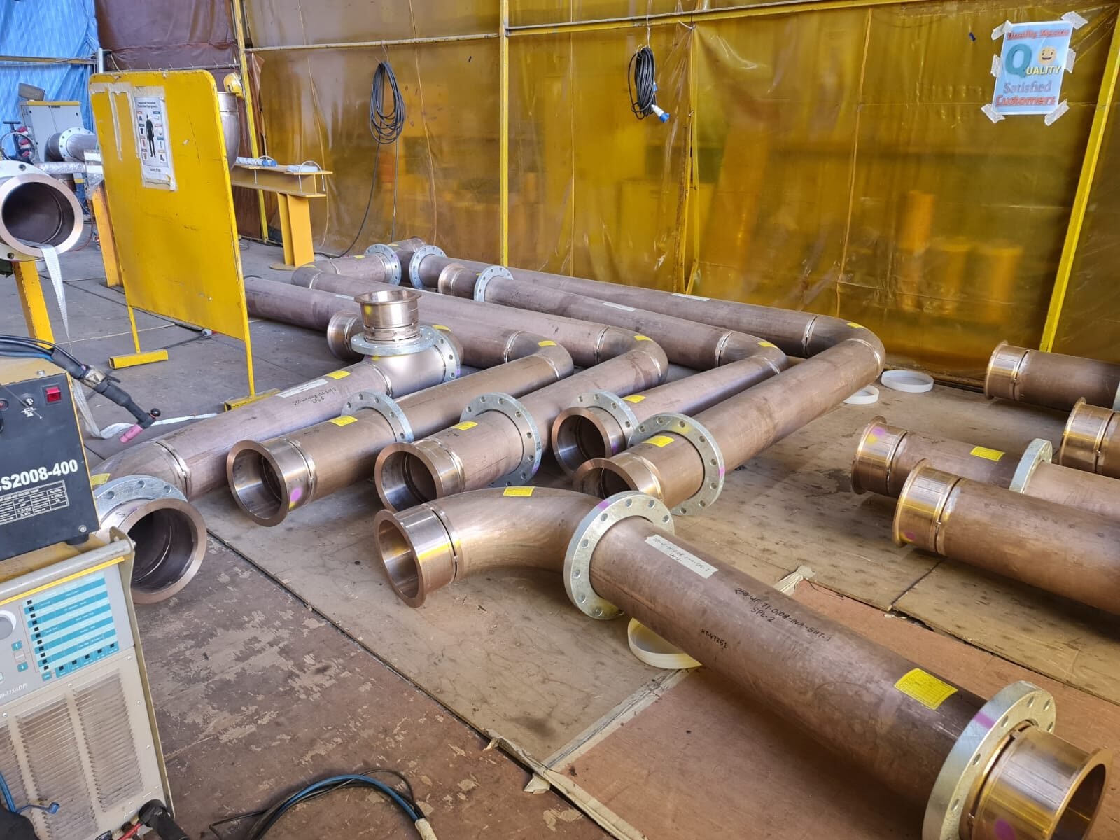 Flanged carbon steel pipe spools laid out in a screened welding bay